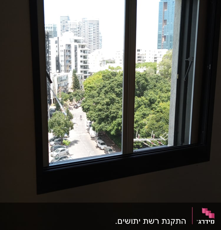חלון אלומיניום עם נוף עירוני ברקע